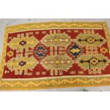 Kelim rug with a repeating medallion design on a red ground with borders, 8ft x 4ft10ins