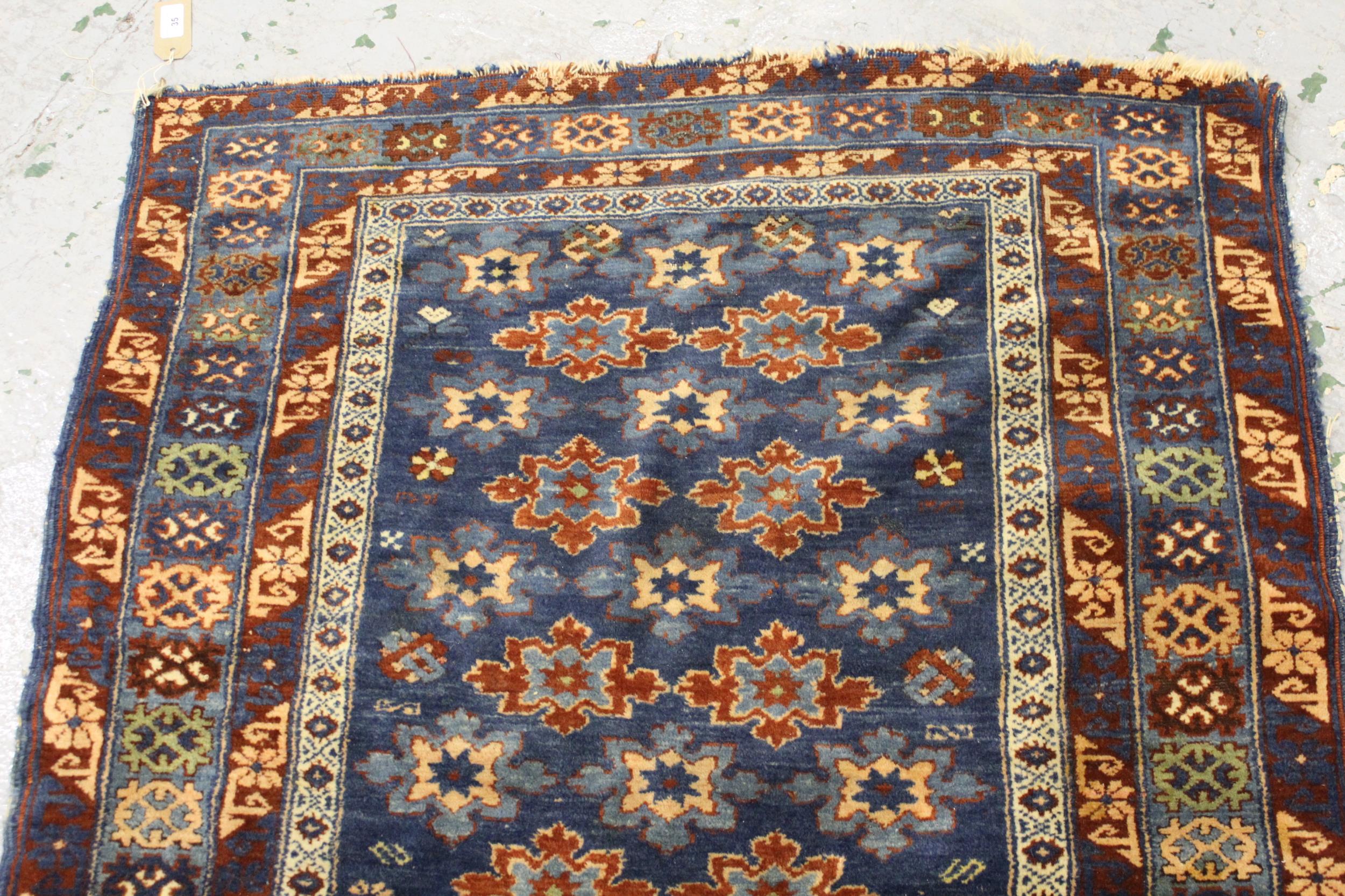 Small Belouch rug with an all over stylised flower head design on a blue ground with borders, 4ft - Image 2 of 4