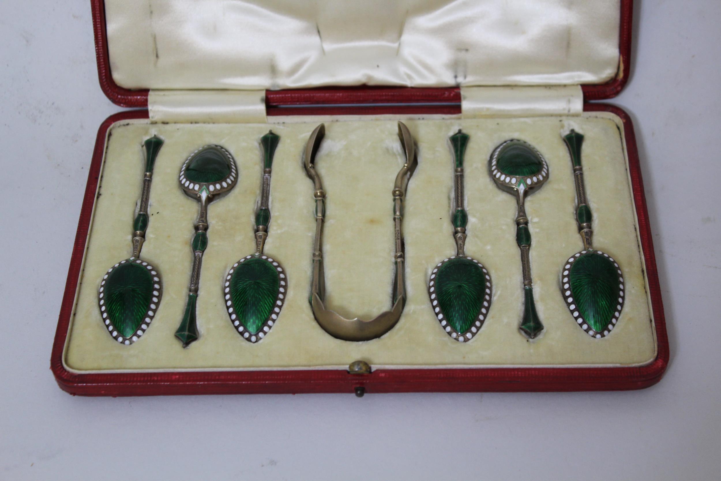 Set of six Norwegian silver gilt and enamel decorated spoons with sugar tongs, with makers mark ' MH