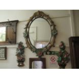 Reproduction carved and painted oval wall mirror of floral design, 42.5ins x30ins approximately,