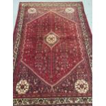 Modern Qashqai carpet with a medallion and all over stylised floral design on a deep red ground with