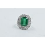 18ct White gold ring set with central emerald surrounded by two bands of diamonds with diamond set