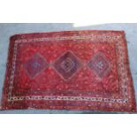 Shiraz carpet with a triple pole medallion and all-over stylised design on a red ground with