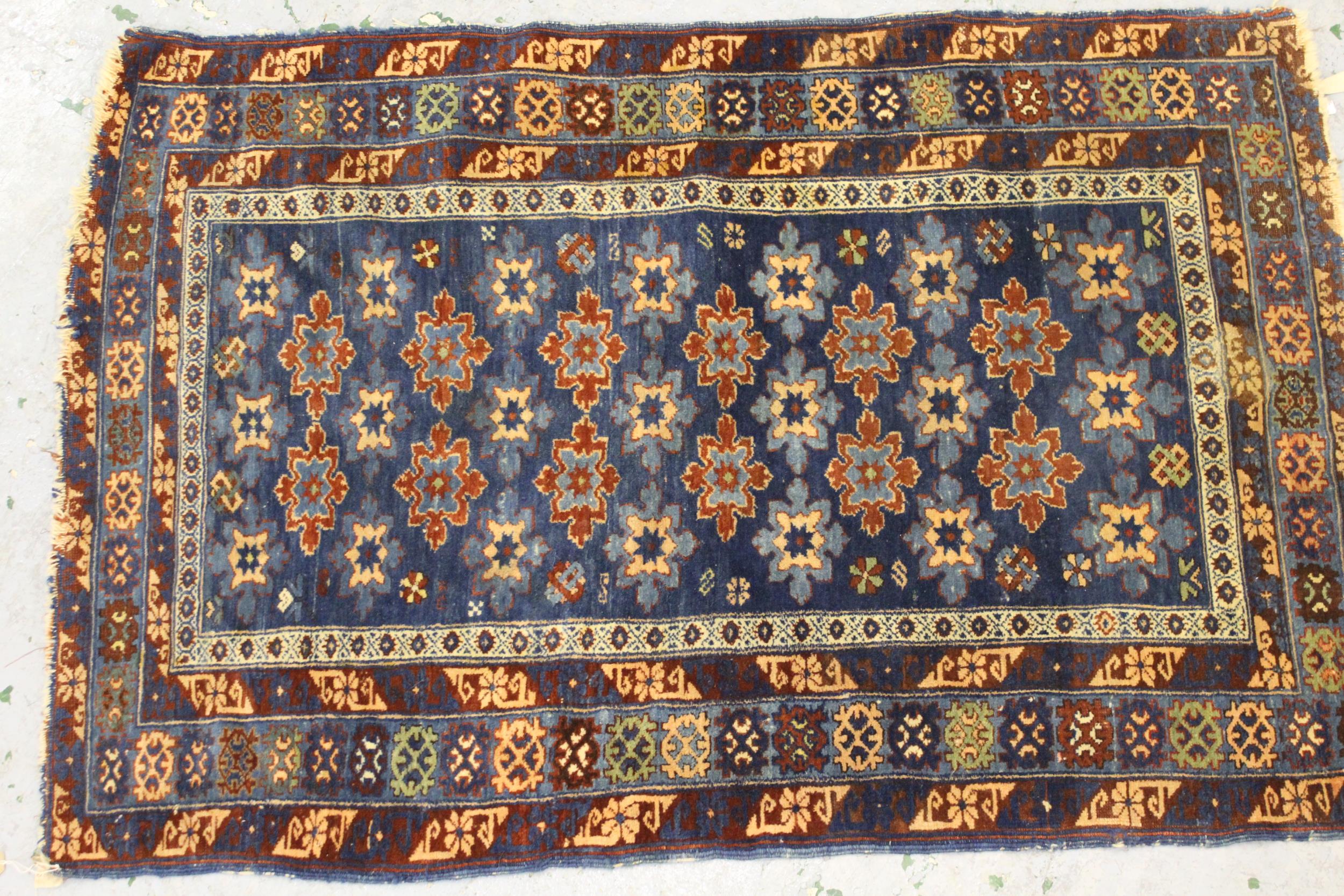 Small Belouch rug with an all over stylised flower head design on a blue ground with borders, 4ft