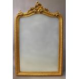 A ROCOCO STYLE GILT FRAMED OVERMANTLE MIRROR, the arch topped bevel edged plate in a moulded and