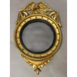 A REGENCY GILTWOOD CONVEX WALL MIRROR, the broad convex mirror plate within a moulded ebonised