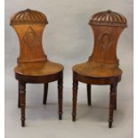 A PAIR OF LATE GEORGE III MAHOGANY HALL CHAIRS, each with waisted backs with central carved