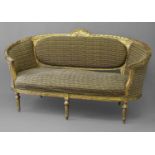 A LOUIS XVI STYLE GILTWOOD SETTEE, with rounded arms and leaf carved gilt frame surmounted by a