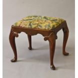 A QUEEN ANNE STYLE WALNUT FRAMED STOOL, the rectangular top with rounded corners with needlework