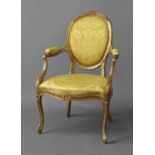 A FINE GEORGE III GILTWOOD ARMCHAIR, with an oval upholstered back beneath a ribbon tied cresting