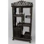 A CHINESE HARDWOOD DISPLAY CABINET, with allover scrolling carved foliate decoration, with an