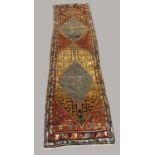 NORTH WEST PERSIAN RUNNER, circa 1920. The chestnut brown field with two medallions enclosed by