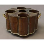 A BRASS AND COPPER WINE COOLER, with fittings for four bottles surrounding a central ice hole, of