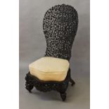 AN ANGLO-BURMESE HIGH BACKED CHAIR, the dished back with allover elaborate pierced and carved