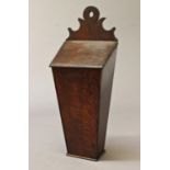 A GEORGE III OAK CANDLE BOX, of traditional form with scrolling and shaped top, sloping lid and