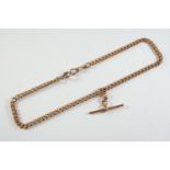 A 9CT GOLD CURB LINK WATCH CHAIN suspending a 9ct gold 't' bar, 38cm long, 31.8 grams