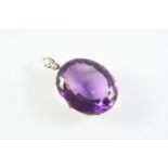 AN AMETHYST AND DIAMOND PENDANT the large oval-shaped amethyst set in gold, with two circular-cut