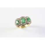 AN EMERALD AND DIAMOND TRIPLE CLUSTER RING mounted with three oval shaped emeralds, each within a