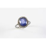 A SAPPHIRE AND DIAMOND CLUSTER RING the cushion-shaped sapphire weighs approximately 4.80 carats and