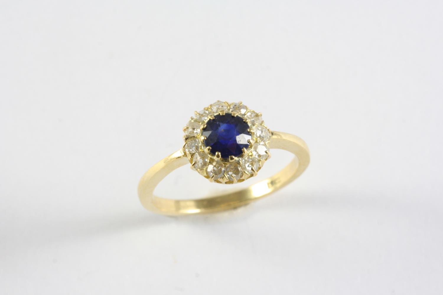 A SAPPHIRE AND DIAMOND CLUSTER RING the circular-cut sapphire is set within a surround of circular-