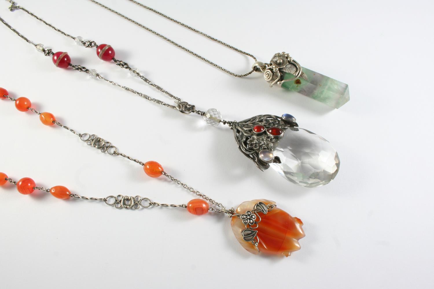 AN ARTS AND CRAFTS SILVER, CRYSTAL,MOONSTONE AND CARNELIAN PENDANT the pear-shaped crystal drop with