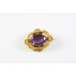 A VICTORIAN GOLD AND AMETHYST BROOCH the oval-shaped amethyst is set within an ornate and wirework