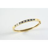 A GOLD, SAPPHIRE AND DIAMOND HALF HINGED BANGLE the 18ct gold bangle is mounted to one side with