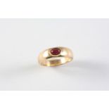 A RUBY AND GOLD RING the gold band is mounted with an oval-shaped cabochon ruby. Size M