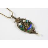 AN ENAMEL AND SILVER GILT PENDANT depicting a woman in a canoe amongst foliage, with enamel, gem set