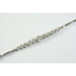 A DIAMOND BRACELET formed with eleven circular collet set diamonds, on an expanding bracelet, 15.5cm