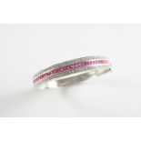 A RUBY AND DIAMOND HALF HINGED BANGLE set to one side with a line of calibre-cut rubies within a