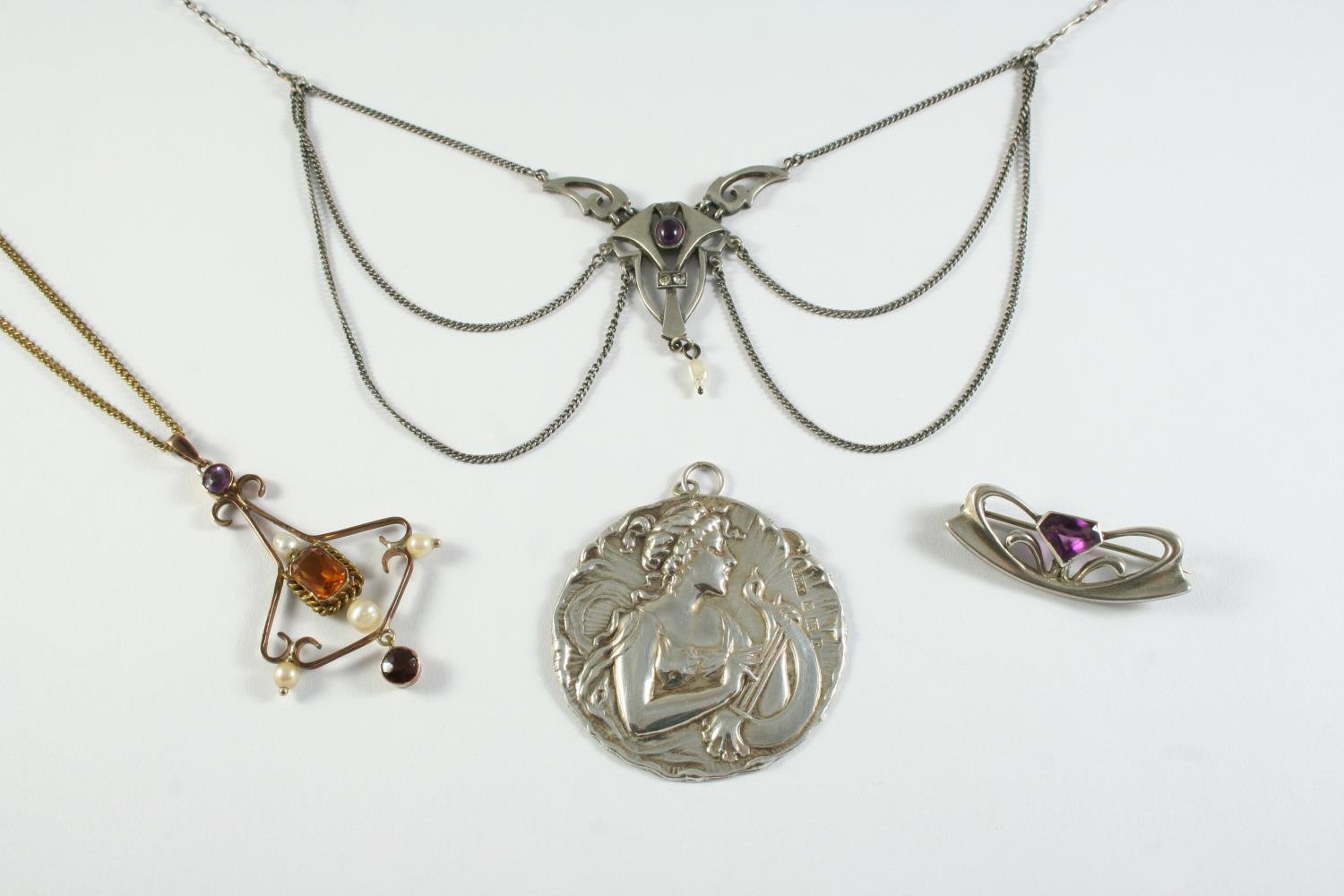 AN ART NOUVEAU SILVER PENDANT depicting a woman with flowing hair playing a lyre, maker's initials