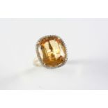 A TOPAZ AND DIAMOND CLUSTER RING the oval-shaped topaz is set within a surround of circular-cut