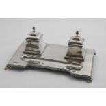 AN EARLY 20TH CENTURY INKSTAND on a shaped rectangular base with bracket feet, reed and ribbon