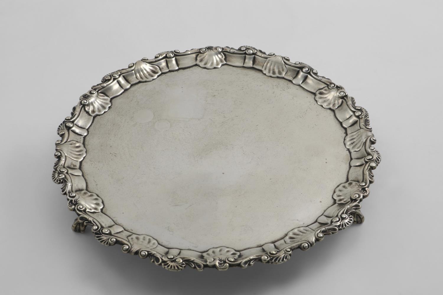 AN EARLY GEORGE III SALVER of shaped circular outline with three ball & claw feet and a border of