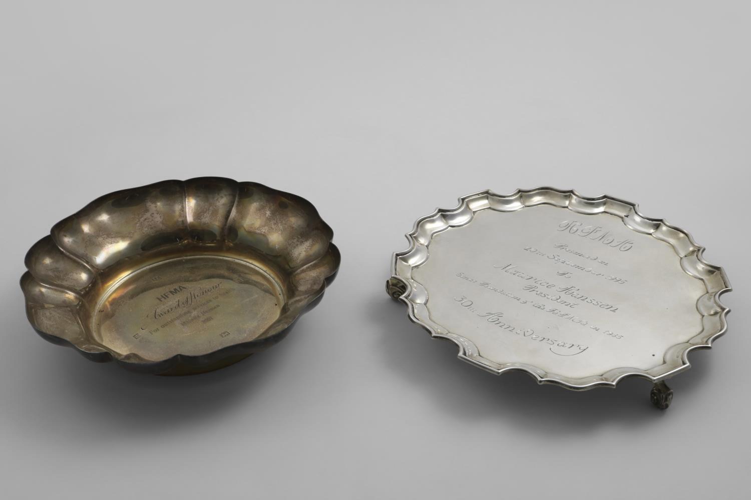 AN EDWARDIAN SALVER of shaped circular outline with a moulded border, scroll feet and a later