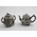 A GEORGE III SMALL REPOUSSE-WORK TEA POT with chinoiserie decoration and four feet, the cartouches
