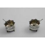 A PAIR OF VICTORIAN SALTS with shaped and everting rims and chased decoration, resting on four