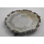 A VICTORIAN PRESENTATION SALVER of shaped circular outline with a border of husks & scrolls and