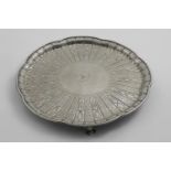 A VICTORIAN SALVER of shaped circular outline on scroll feet, chased with radiating fluted