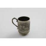 AN EARLY 20TH CENTURY INDIAN MUG with a leaf-capped scroll handle chased with native figures