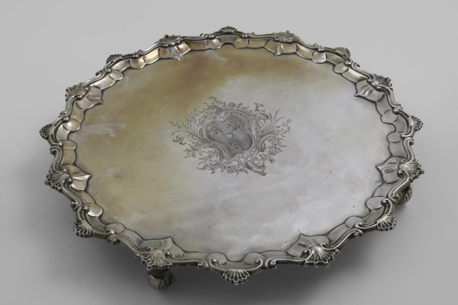 AN EARLY GEORGE III SALVER of shaped circular outline with a shell and scroll border, and scroll
