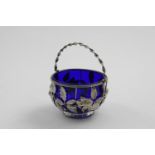 A VICTORIAN SWING-HANDLED SUGAR BASKET with a blue glass liner, the wirework sides decorated with