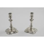 A PAIR OF GEORGE II CAST CANDLESTICKS on shaped square bases, with knopped and shouldered