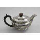 A GEORGE III SQUAT CIRCULAR TEA POT with a chased frieze of repeating leaves around the sides and