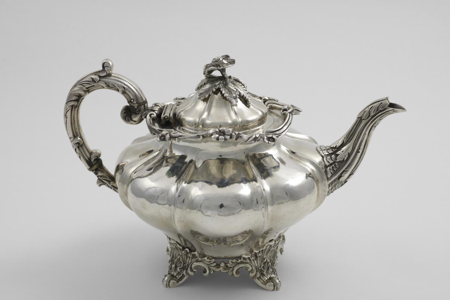 AN EARLY VICTORIAN SCOTTISH PROVINCIAL TEA POT with a shaped circular body, a leafy scroll handle,