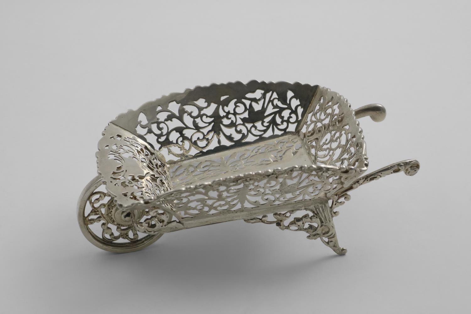 AN EDWARDIAN BONBON DISH in the form of a wheelbarrow with pierced, engraved and applied decoration,