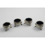 A SET OF FOUR GEORGE II SCOTTISH SALTS of squat circular form with scalloped rims, mask and shell