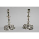 A PAIR OF EARLY GEORGE III CAST CANDLESTICKS on shaped square bases with shell decoration, knopped &