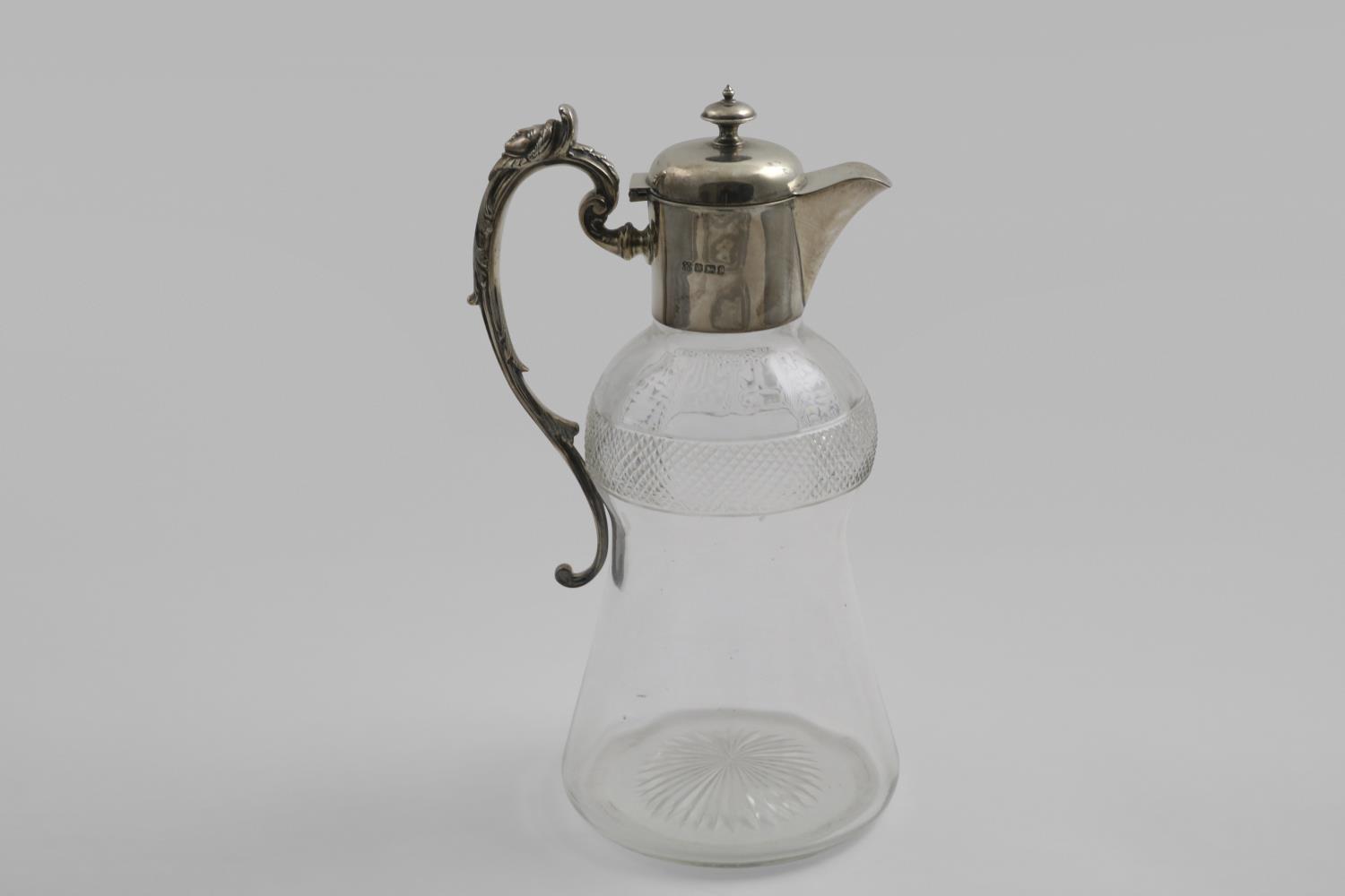 A LATE VICTORIAN MOUNTED CUT-GLASS CLARET JUG with a campana-shaped body, decorative scroll handle